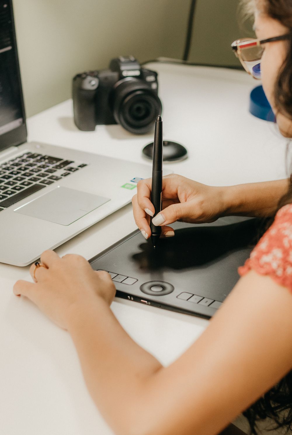 A designer using a pen and graphics tablet beside a laptop